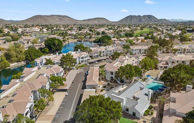A bird's eye view of a residential area with houses, roads, and a lake.