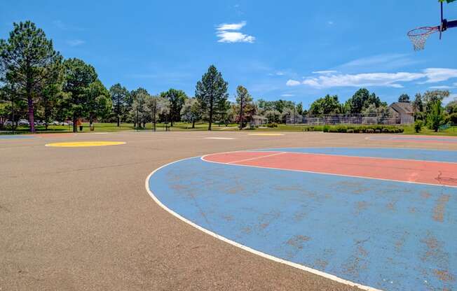 A basketball court with a blue and red surface and a basketball hoop.