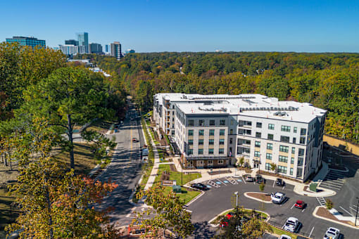 an aerial view of a building with a parking lot and a city in the background