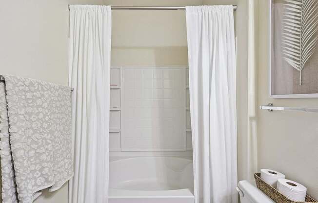 Clean full bathroom with white shower-tub combo and linen storage at Tattersall Village Apartments in Hinesville