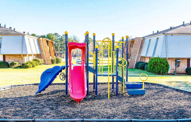 A playground with a red slide and a blue slide.