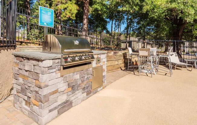 a barbecue grill on a stone wall next to a table and chairs