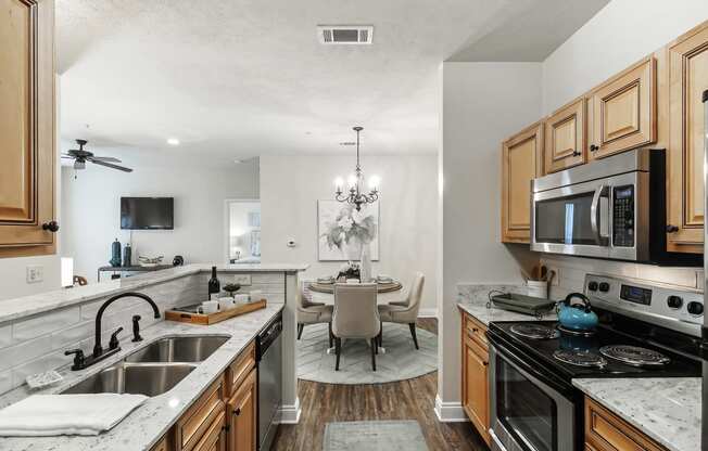 a kitchen with a sink and a stove and a dining room with a table