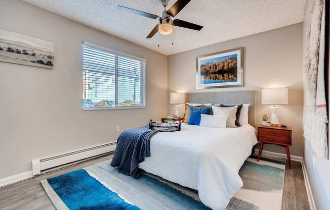 A bedroom with a bed, a ceiling fan, and a rug at Mountain Vista Apartments, Lakewood, Colorado