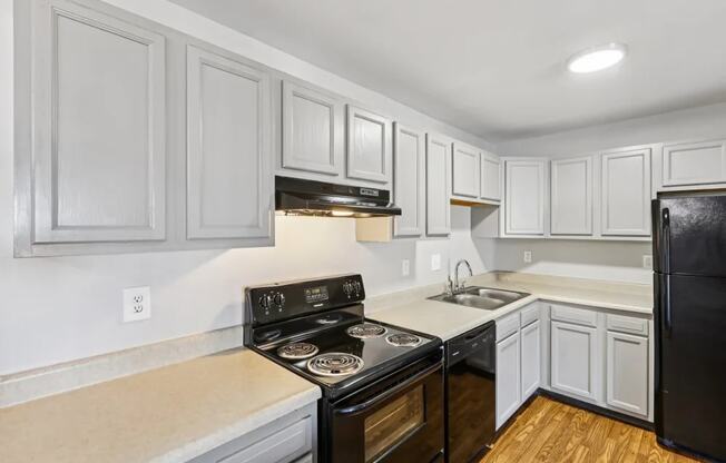 A kitchen with a black stove top oven and white cabinets.