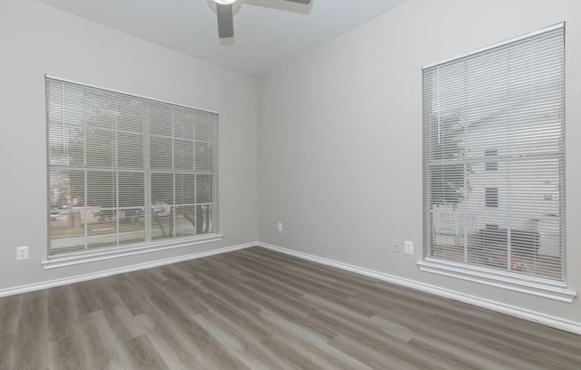a bedroom with two windows and a ceiling fan