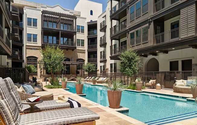 A pool surrounded by patio furniture and potted plants.