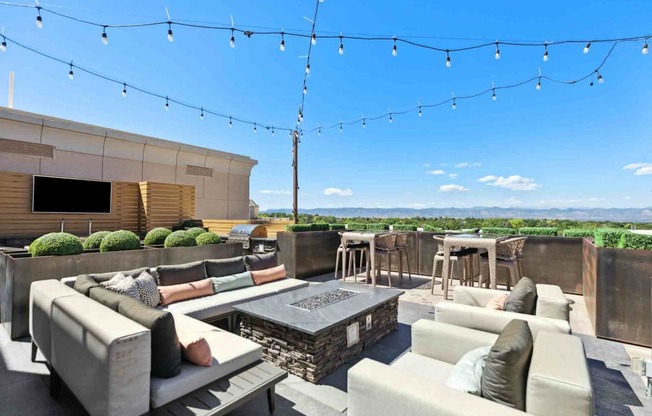 a rooftop patio with couches and chairs and a fire pit