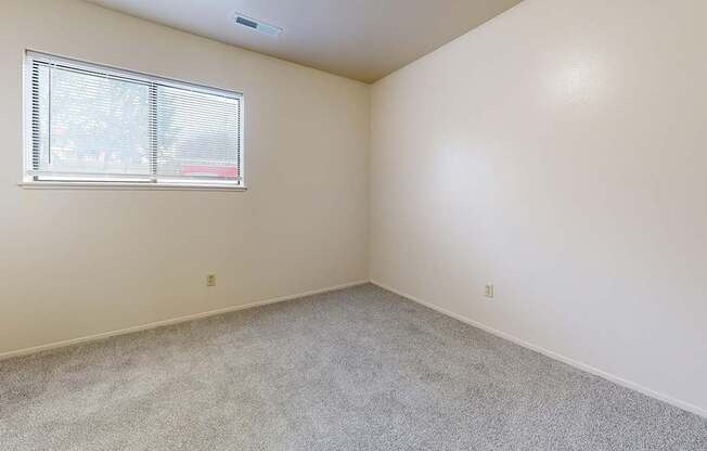 A bedroom with a window and carpeted floor at Irish Hills Apartments, South Bend, Indiana