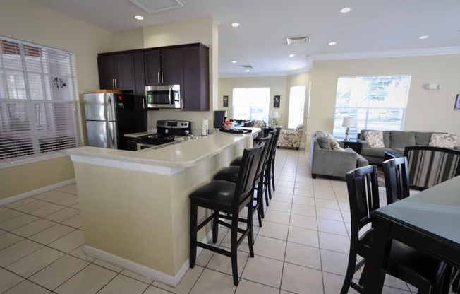 an open kitchen and living room with a bar and chairs