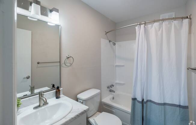 a bathroom with a white sink and toilet next to a white bathtub with a shower curtain