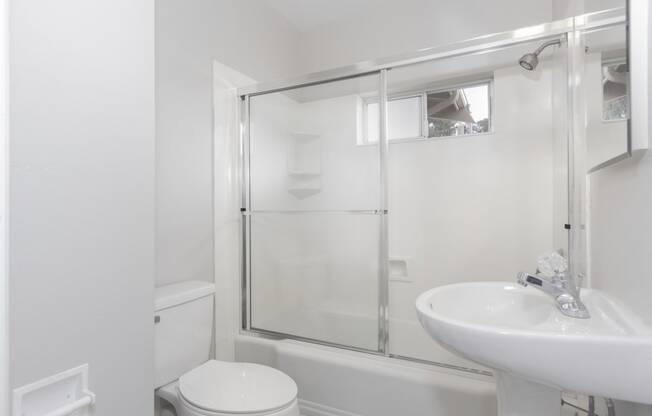 a white bathroom with a shower and a sink