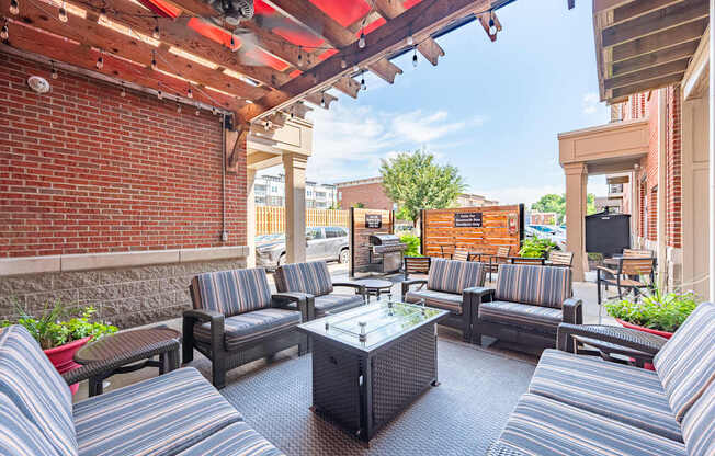 A patio with striped couches and a glass table.