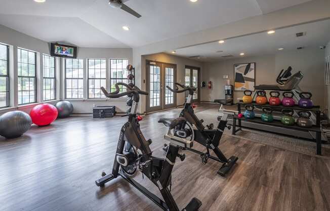 a modern apartment complex gym with weights and cardio equipment and windows