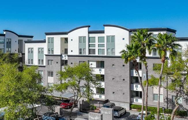 A modern apartment complex with a parking lot in front.