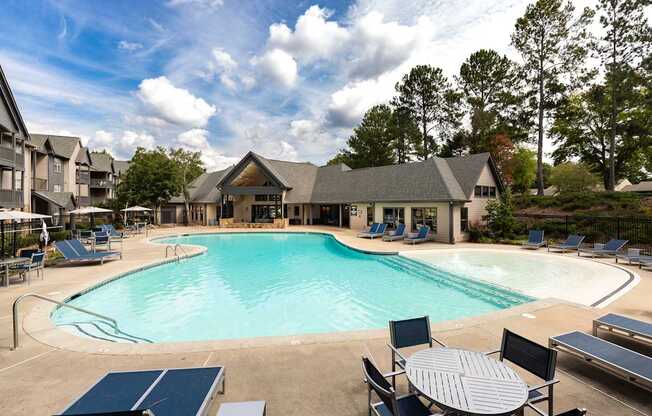 A large outdoor swimming pool surrounded by lounge chairs and umbrellas.