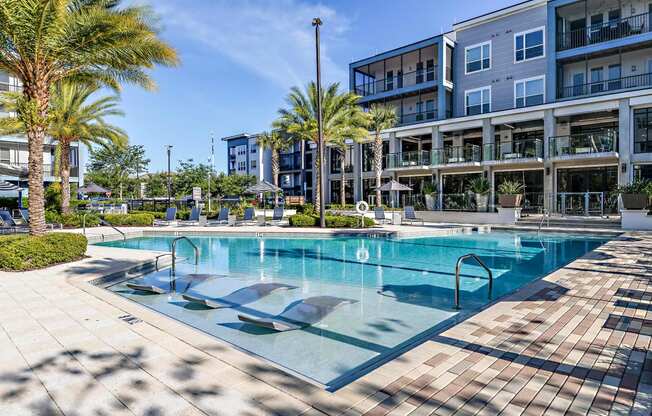 a large swimming pool in front of a building with palm trees