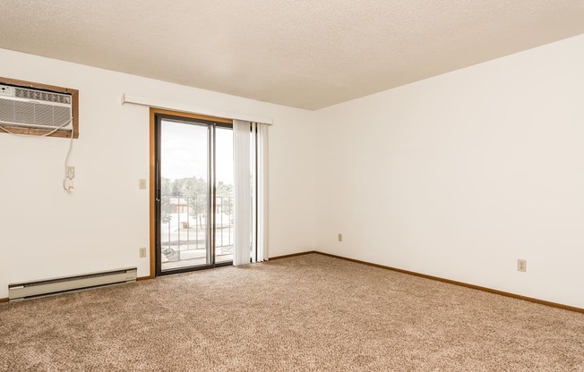 Grand Forks Harrison Apartments. An empty living room with a sliding glass door to a balcony