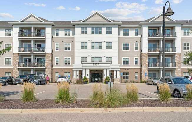 A large apartment complex with multiple balconies and cars parked in the lot.