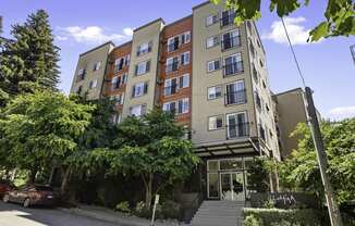 Front view of property building with an awning and trees for shade at Illumina Apartment Homes, Seattle, WA
