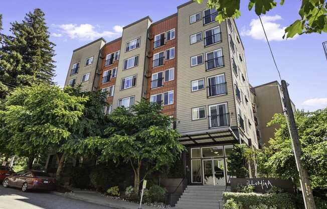 Front view of property building with an awning and trees for shade at Illumina Apartment Homes, Seattle, WA