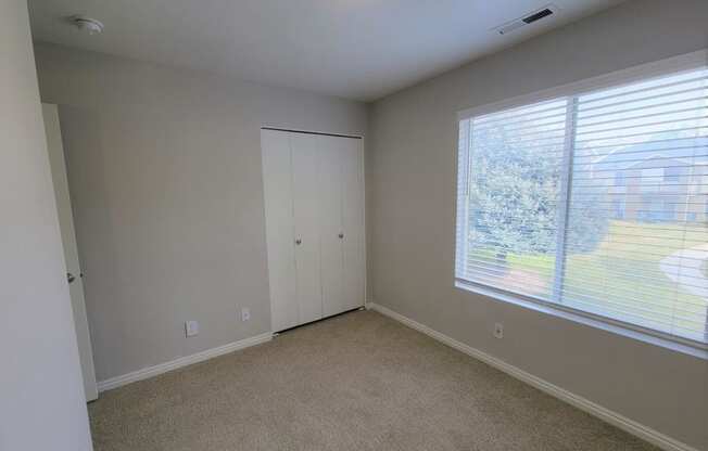 a bedroom with a large window and a closet