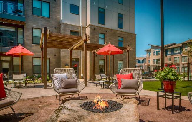 a fire pit in the middle of a patio with chairs and umbrellas