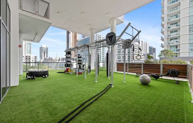 a gym on the roof of a building with green grass and a ball and weights