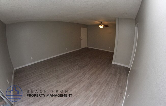 an empty living room with wood flooring and a ceiling fan