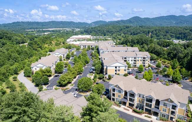 an aerial view of a large apartment complex with trees and mountains in the background