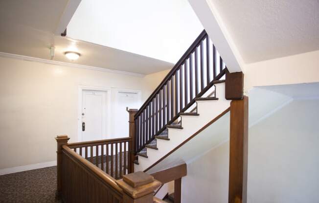 A staircase with a wooden handrail and a skylight above.