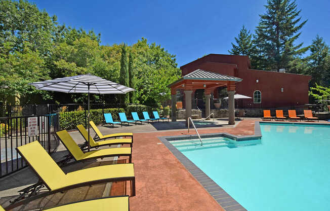 A pool area with a red building and yellow sun loungers.