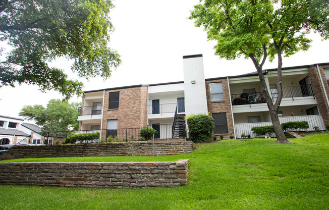 the outlook of an apartment building with green grass and trees