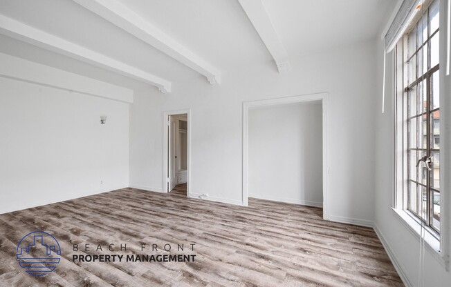 a living room with white walls and wood floors and a doorway