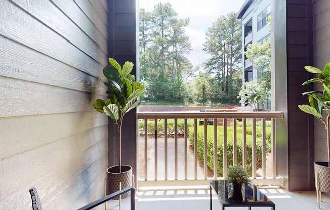 A balcony with a table and two potted plants.