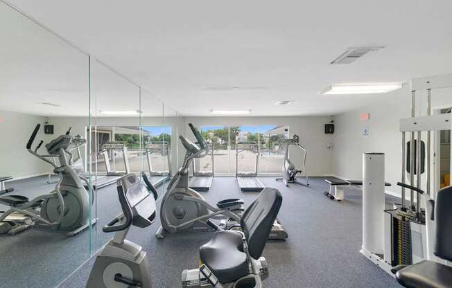 A gym with a variety of equipment including treadmills, stationary bikes, and weight machines.