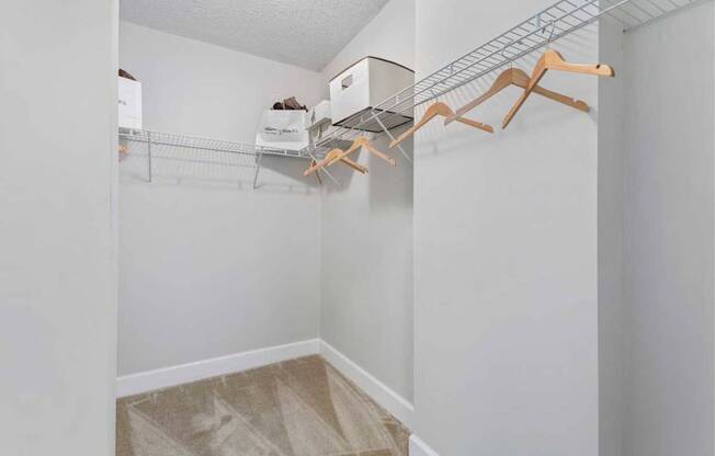 A white closet with a metal rack and wooden hangers.