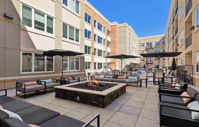 a patio with chairs and umbrellas and a fire pit