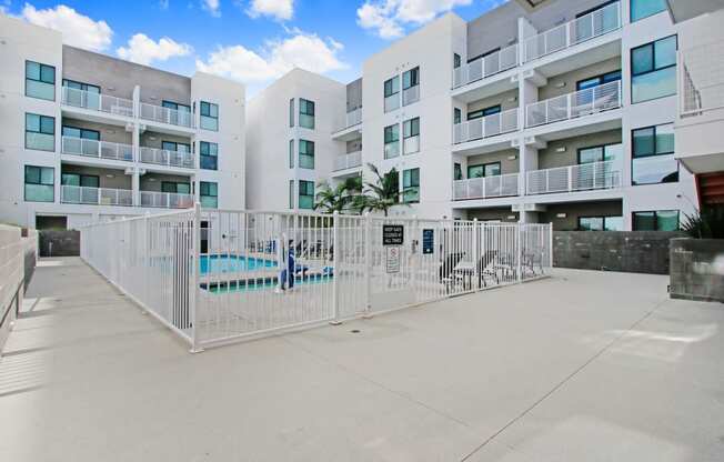 an apartment building with a fence and a pool in front of it