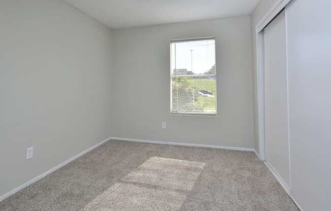 an empty room with a window and carpet