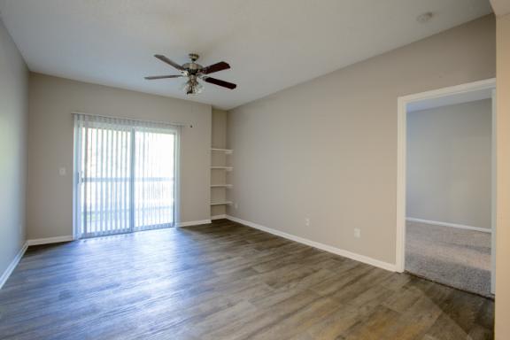 A room with a ceiling fan and sliding glass doors.