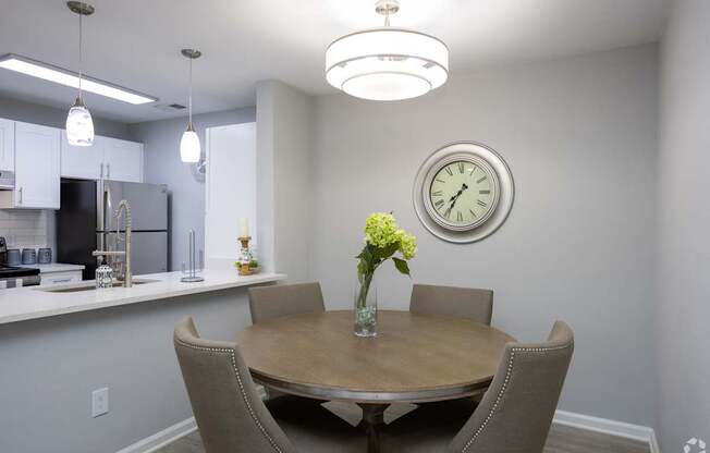 A dining room with a table set for two and a clock on the wall.