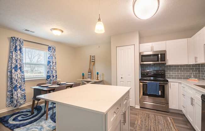 a kitchen with white cabinets and a white island with a blue and white rug