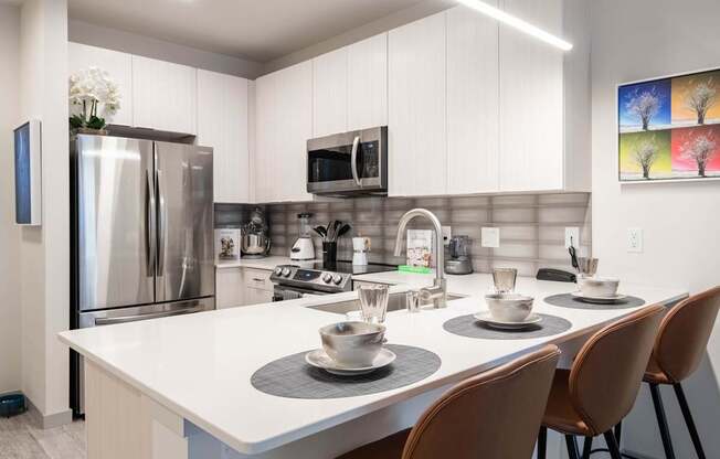 A modern kitchen with a white table and chairs.