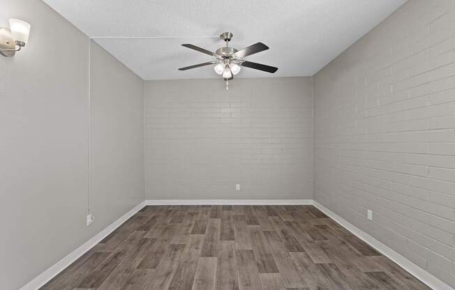 A room with a ceiling fan and wooden flooring.
