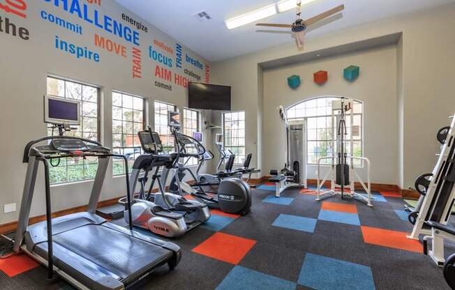 a gym with various exercise equipment and windows