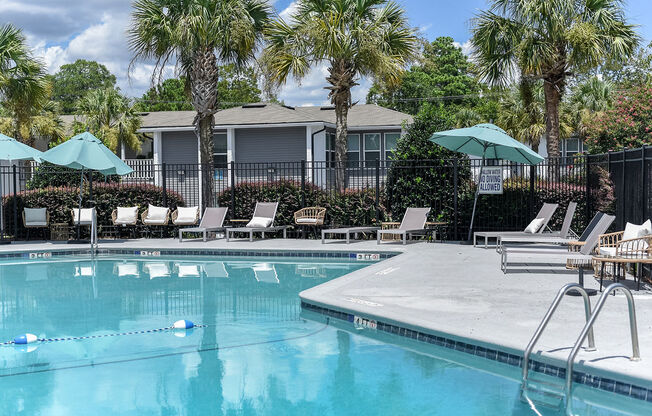 a resort style pool with chaise lounge chairs and umbrellas