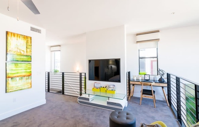 A living room with a tv and tv stand and desk and chair