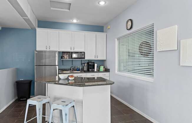 a kitchen with a bar and stools in front of a window and a counter