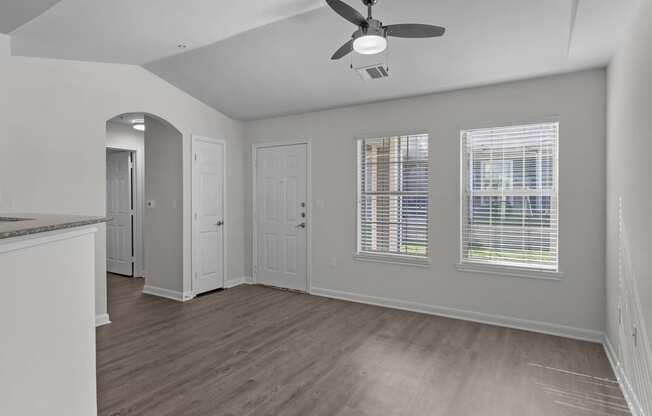 an empty kitchen and living room with a ceiling fan